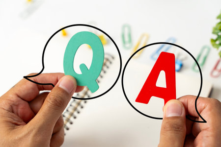 Q and A written on a notepad Work desk with electronic equipment computer and paper wooden table...