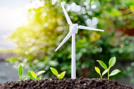 The Sapling are growing from the soil with wind turbine farm on blue sky background. Energy clean electricity renewable energy concept.の写真素材