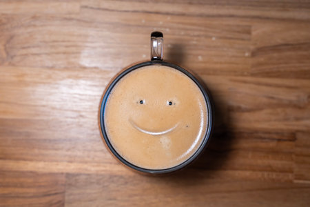 Good morning coffee smile cup on wooden background. Cup of delicious hot coffee with foam and smile...
