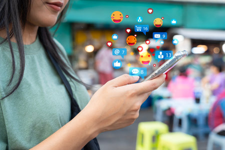Woman hand using a social media marketing concept on mobile phone with notification icons of like, message, comment and star above mobile phone screen.の写真素材