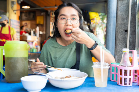 Eating action with asian food concept. Using chopstick holding noodle in white glazed bowl. Asian women use chopstick eating delicious noodle in white bowl , focused on noodle.の写真素材