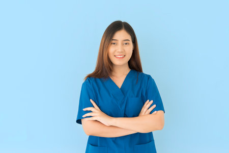 A woman in a blue scrubs shirt is smiling and crossing her arms. She is a nurse or a doctor on blue...