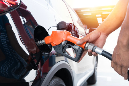 Refueling the car at a gas station fuel pump. Man driver hand refilling and pumping gasoline oil the...