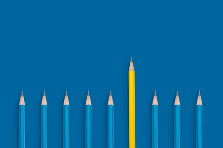 A row of pencils with one yellow pencil in the middle. The pencils are all blue. Standing out from the crowd concept.の写真素材