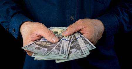 Big pile of money dollars in the hand. Close up of businessman counts money in hands. American...