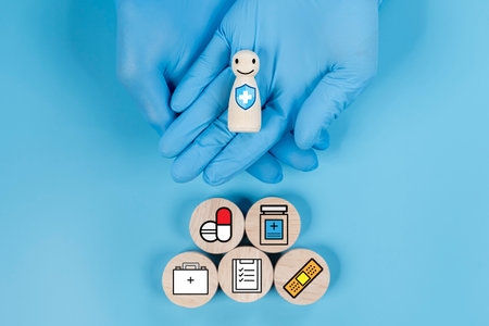 Doctor hand holding wooden block with smiling face with healthcare-related icons, such as a cross, a wheelchair, a syringe, and a medical kit, symbolizing healthcare services and supportの写真素材