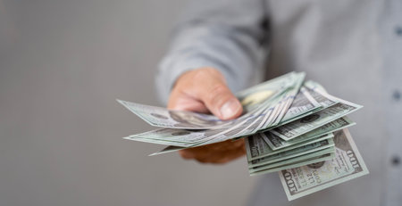 Close up of someone hands holding and counting American dollar banknotes in her hand. A Person...