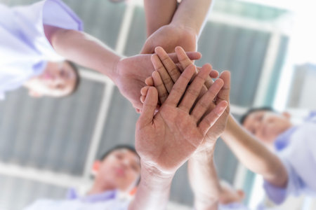 Diverse Hands Stacked in Unity and Teamwork. Many children stacking hands together. Symbol for teamwork and motivation.の写真素材