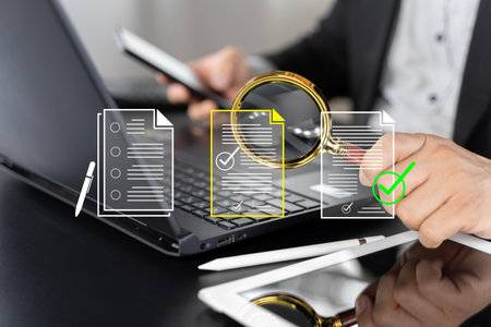 Electronic document check and data information searching online, files manager concept. Yellow documents file icon appear on magnifying glass in businessman hand while working with laptop computer.の写真素材