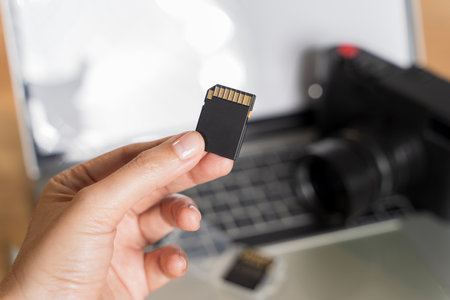SD Card with camera. Inserting high-capacity memory card into photo camera outdoors. Photographer's...