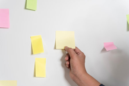 Close up hand people business man  notes pad in the wall at meeting room. Sticky post it note paper reminder schedule board. Colorful variety copy empty space. soft focus.の写真素材