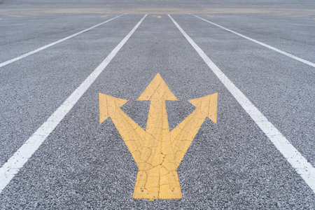 Painted and weathered yellow arrows on a street. Three-way direction arrow sign.の写真素材