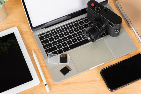 Top view. Flat lay. Laptop, external hard drive, modern digital camera. Two sd memory cards and lens on gray background. Photographer's equipment, smartphone and tablet with blank screen.の写真素材