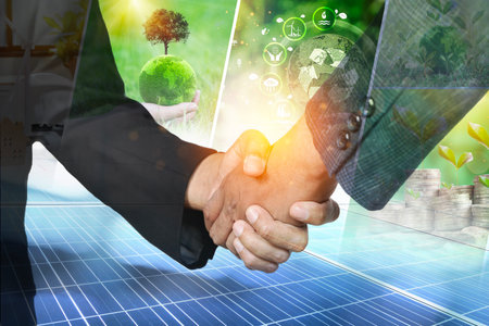 Businessman is hand shaking. Green sustainable or ESG of solar and windmill energy produced from...