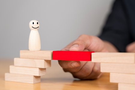 Midsection of businessman playing with toy blocks on table. Take the next steps to your goals. Business development concept. Building bridge with wooden toy blocks on tableの写真素材