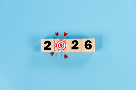 Red bullseye target with arrow and 2026 wooden blocks symbolizing business goals and planning. 2026 year with the target which prints screens on wooden cube blocks, ideas for Business.の写真素材
