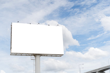 Large empty white billboard with bright sky and cloud background. Ideal mockup template for outdoor advertising, marketing design, announcement display, and commercial promotion. Clipping path.の写真素材