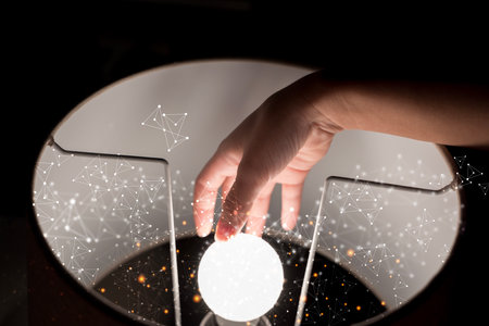 A human hand touching a glowing orb with abstract digital network particles floating around. Futuristic concept of connection, light, innovation, artificial intelligence, and human interaction.の写真素材