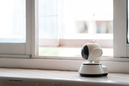Modern smart security camera installed on indoor windowsill for real-time surveillance, safety,...