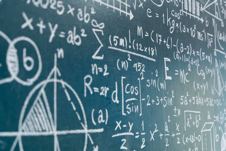 Close-up view of a chalkboard covered with mathematical equations, graphs, and scientific formulas....