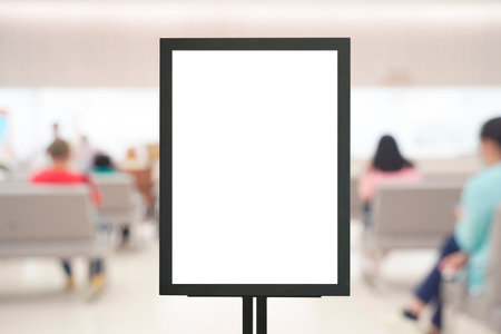 Empty advertising sign mockup stand in hospital lobby with patients seated in background. Ideal for promoting healthcare services, medical info, or public health announcement visual.の写真素材