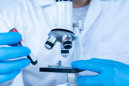 Scientist analyzing blood sample under microscope in laboratory, representing medical research,...