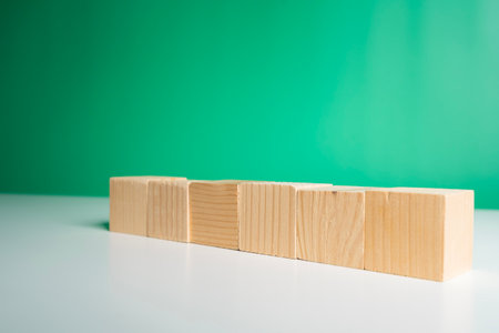 Closeup of wooden blocks aligned on white table with bright green background, representing education, learning, creativity, business planning, and abstract concept for success and growth visualizationの写真素材