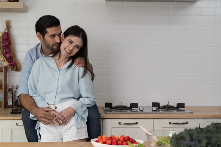 Happy romantic couple embracing in modern kitchen, symbolizing love, family bonding, healthy lifestyle, organic food, bright emotions, togetherness, and joyful home cooking moments full of happiness.の写真素材