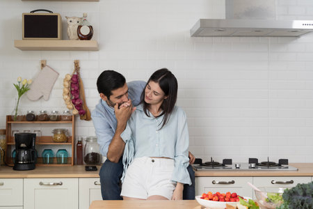 Young romantic couple in modern kitchen, man kissing womanâs hand with love and tenderness, representing romance, affection, wellness, family bonding, healthy lifestyle, organic food, joyful emotions.の写真素材