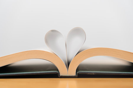 Close up of an open book with its pages folded into a heart shape, symbolizing love, romance,...