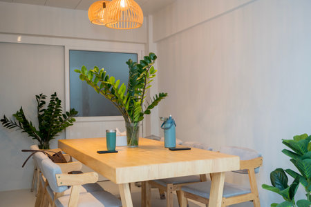 Modern minimalist dining room interior with wooden table, indoor plants, and warm pendant lights....