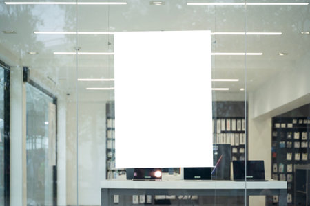 Empty white poster hanging on glass wall of modern shop interior, perfect for advertising, marketing, branding, product promotion, and business design mockup for creative commercial presentation sceneの写真素材