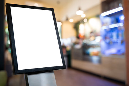 Empty white poster frame standing near cafe counter with blurred background, perfect for advertising, branding, marketing, product promotion, business signage, creative commercial mockup presentation.の写真素材