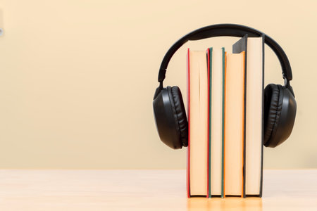 Creative audiobook concept showing stacked books with black headphones, symbolizing modern learning, reading, knowledge, study, digital education, literature and audio entertainment in a minimal setupの写真素材