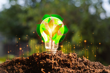 Concept of green energy and sustainability with glowing light bulb growing from soil, recycling symbol, eco friendly innovation, renewable power, environmental protection and circular economy.の写真素材