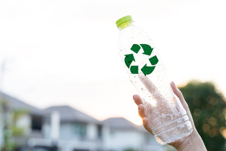 Plastic bottle recycling concept with green recycle symbol held in human hand, representing waste reduction, sustainability, eco friendly lifestyle, environmental protection and responsible plastic.の写真素材