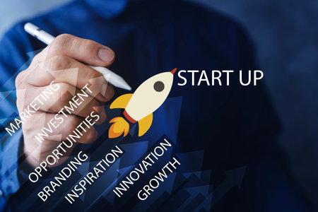 Close-up of hand holding pen with rocket startup icon and rising arrows, illustrating business...
