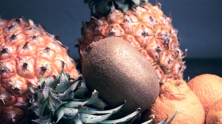 Some summer fruit such pineapple orange on wood table in dark blue background. - Image