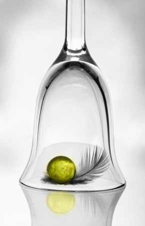 A wineglass, a yellow ball and a featherの写真素材