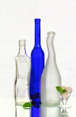 Three bottles and a wineglass with sweetsの写真素材