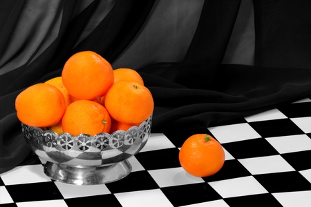 Some tangerines in the metal bowl on the chess boardの写真素材