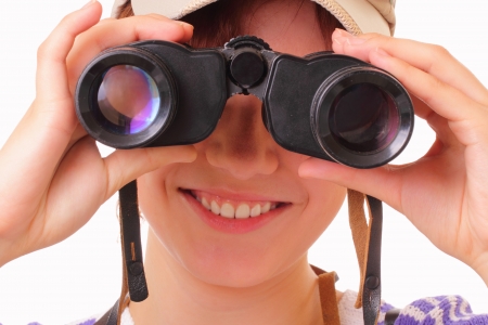 Smiling young girl looking through binocularsの写真素材