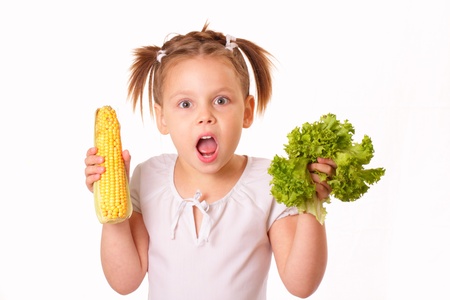 Funny little girl with corn and lettuce in her handsの写真素材