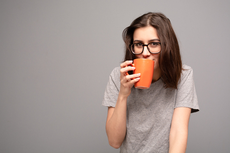 Girl holding cup of hot drink on grey background.の写真素材