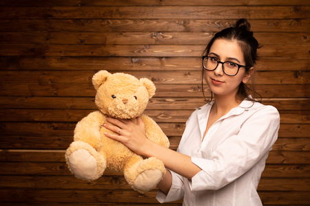 Girl with Teddy bear on the dark wooden backgroundの写真素材