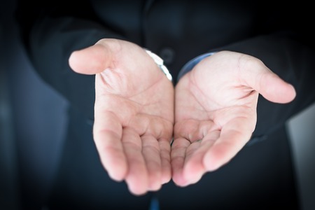 Young businessman extending hands asking for helpの写真素材
