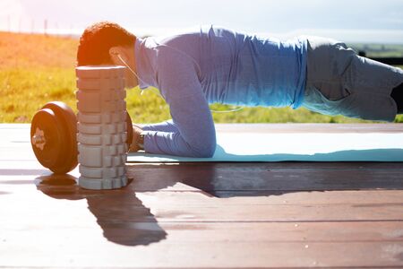 A young man doing yoga exercises on a deck with a beautiful view
