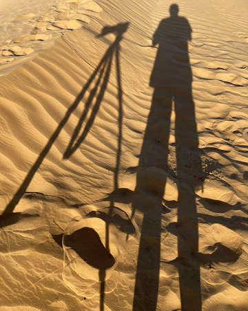 Shadows of the tripod and photographer in the Empty desert, Oman.