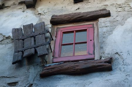 An red window in an old house with wooden shutter