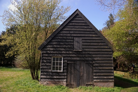 An old black wooden barn at the edge of a forestの写真素材